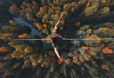 Un funambule marche sur un fil au dessus d'une forêt