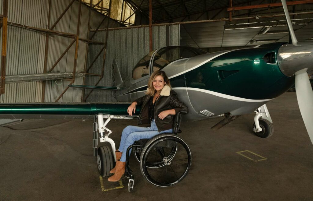 Dorine Bourneton pose à côté de son avion, elle est la première femme handicapée à réaliser de la voltige aérienne