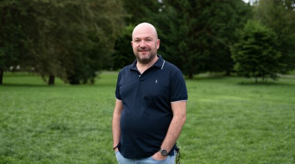 Portrait de Guillaume Limousin en extérieur, debout dans un parc avec des arbres en arrière-plan.